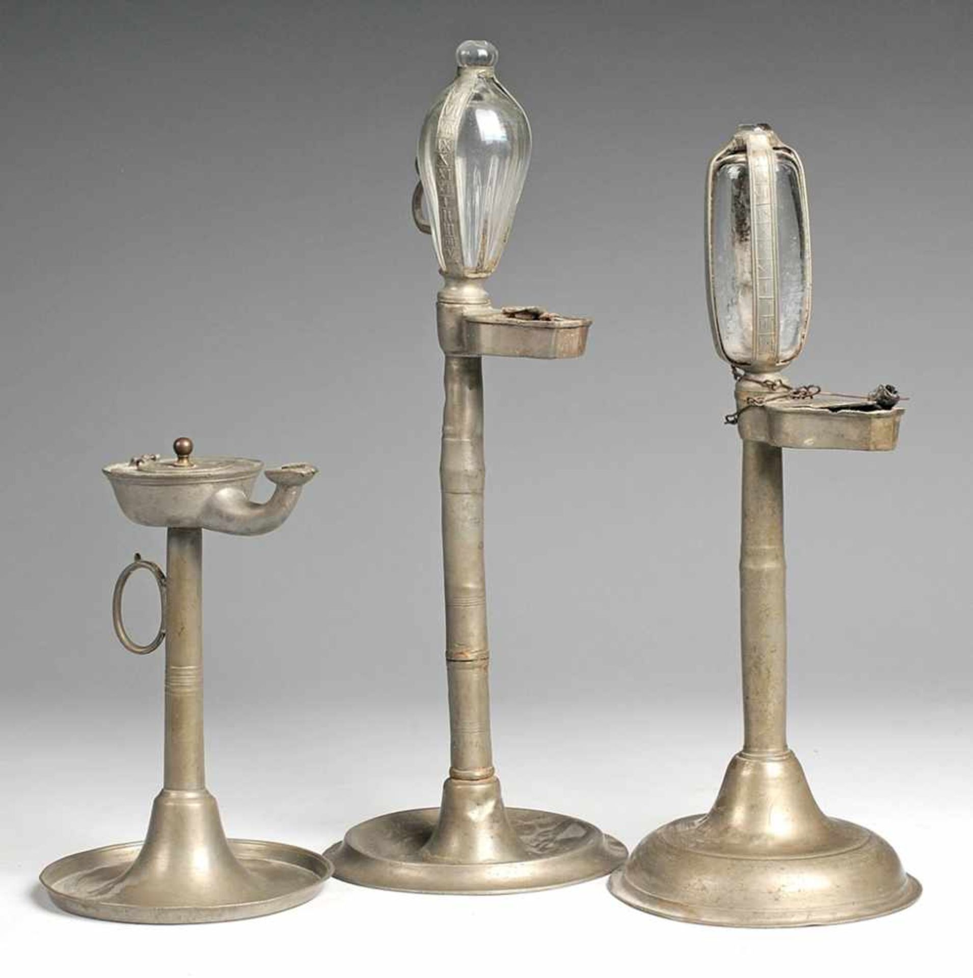 Drei Öllampen Zinn. Teller- bzw. ansteigender Fuß, schlanker Schaft, Öltank, 2 x mit Stundenglas