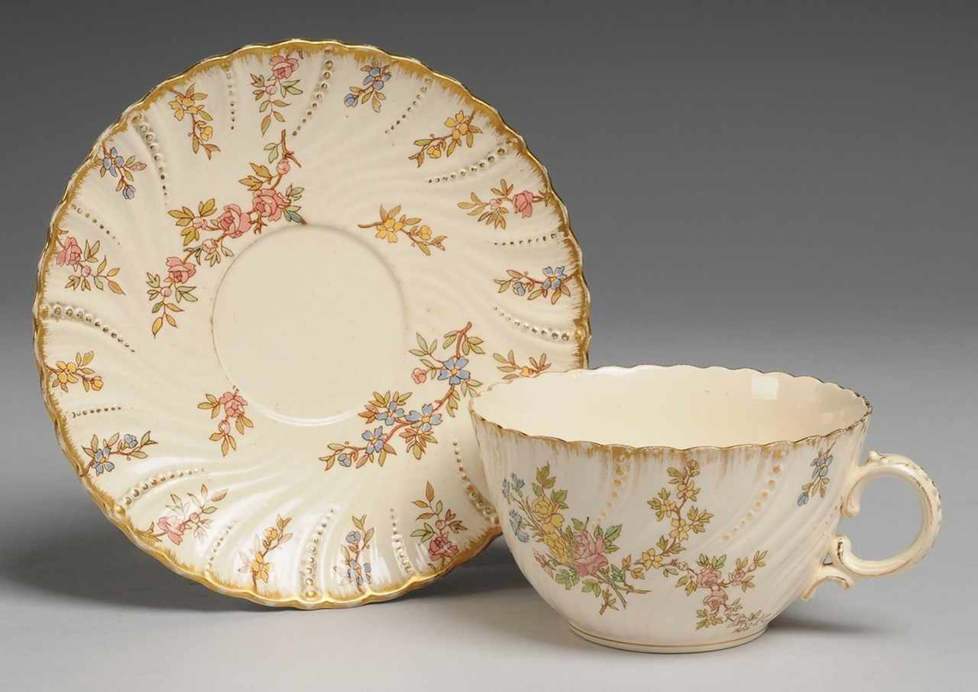 Tasse mit UT "Louis XV." Steingut, cremefarben glasiert. Geschwungen gerippte Wandung bzw. Fahne mit