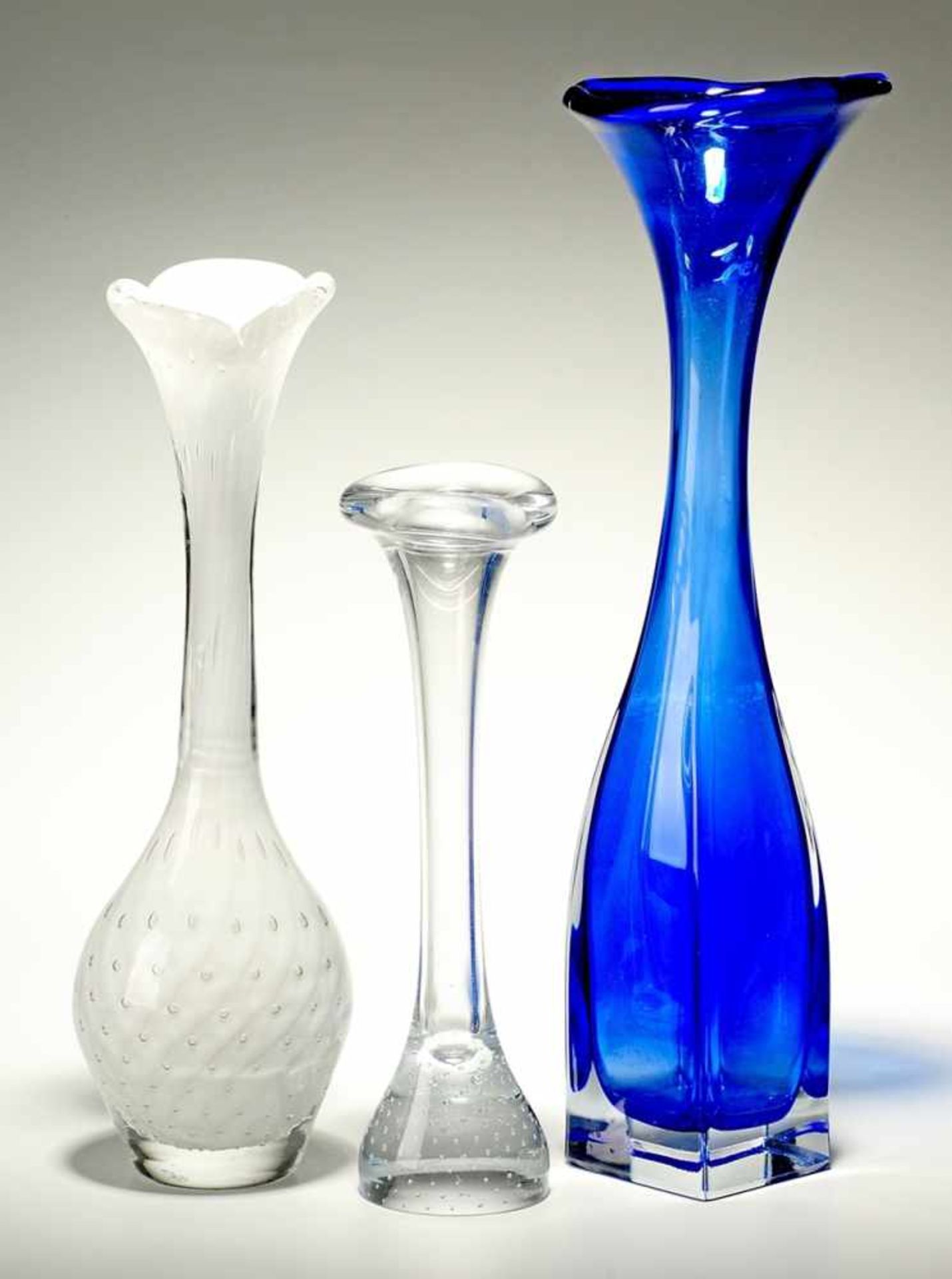 Drei Vasen Dickwandiges farbloses Glas, 1 x kobaltblau bzw. opalweiß unterfangen. Formgeblasen.