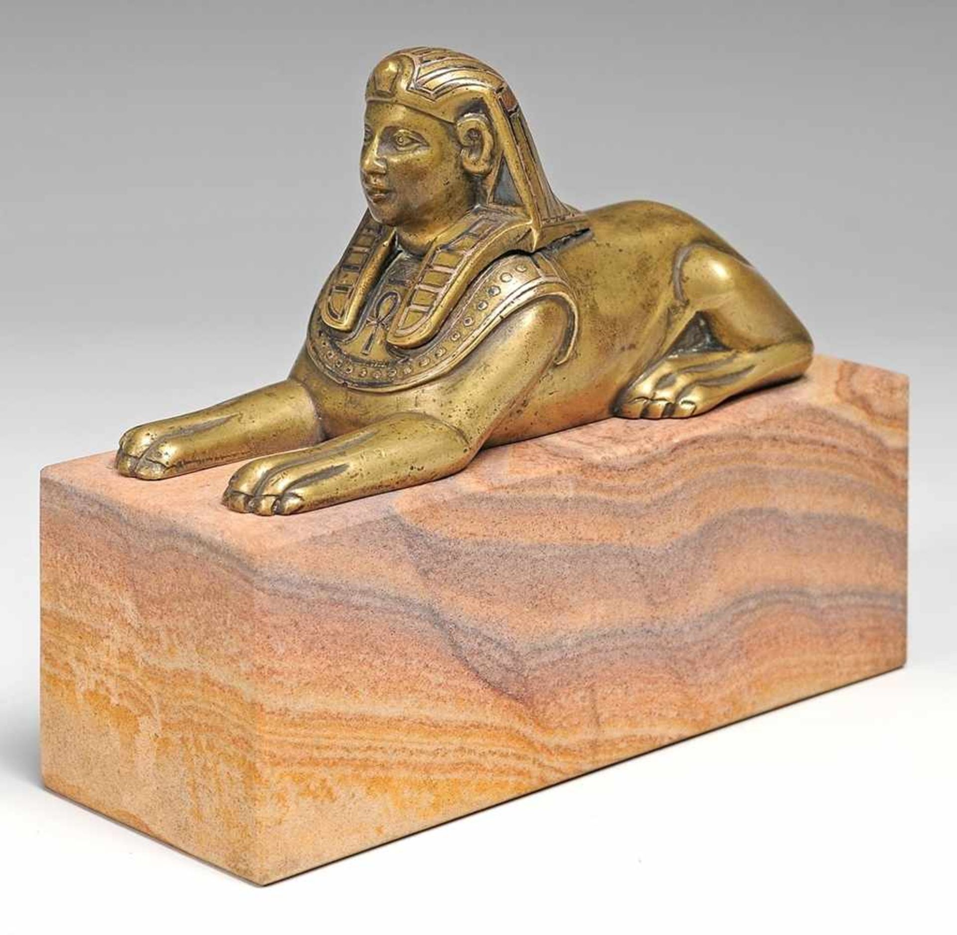 Sphinx Bronze, patiniert. Auf quaderförmigen Sockel (erneuert) Darstellung einer liegenden Sphinx.