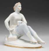 "Schlittschuhläuferin" Weiß, glasiert. Auf ovaler Plinthe Darstellung einer sitzenden