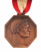 Ehrenmedaille Bronze. Oktogonale Form mit lorbeerbekröntem Männerkopf im Relief. Ordensband.