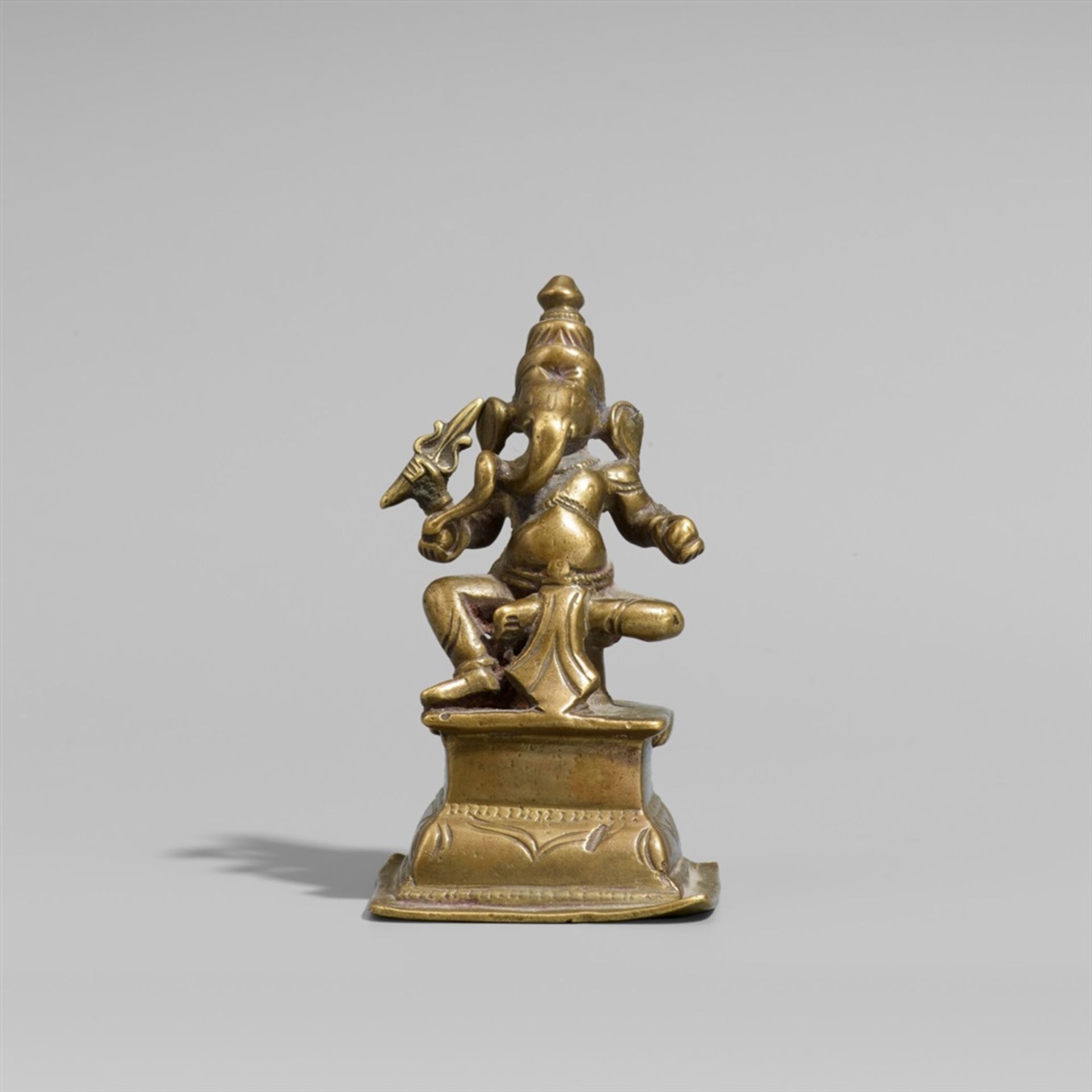 Figur des vierarmigen Ganesha. Gelbguss. 19. Jh. Sitzend auf hohem Sockel, an einer Süßigkeit - Bild 3 aus 3