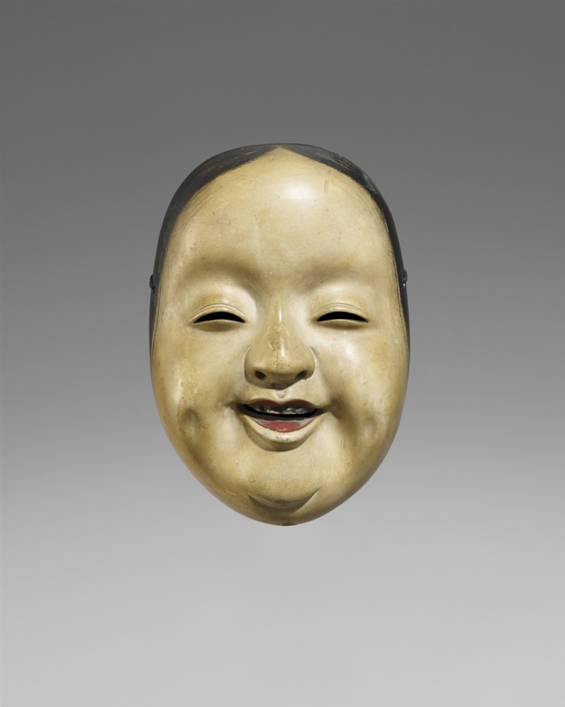 Kyôgen-Maske vom Typ Okame. Holz, farbig gefasst. 18./19. Jh. Freundlich lachend, mit Wangengrübchen