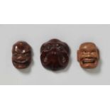 Drei Masken-Netsuke. Holz. 19. Jh. a) Wohl Ikkaku Sennin. b) Groteske Abwandlung einer Buaku-