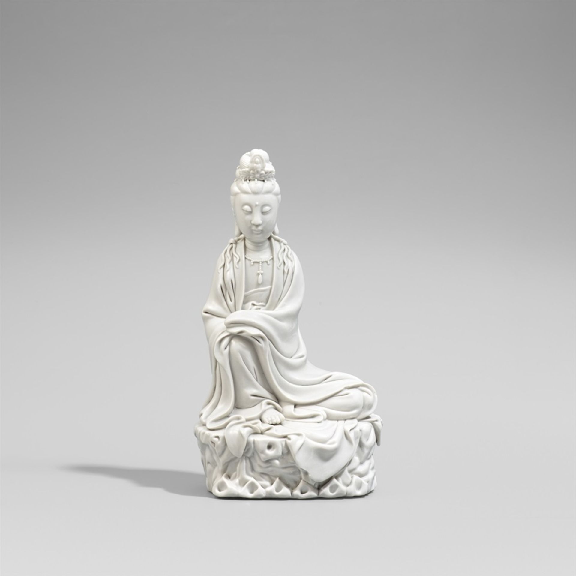 Blanc de chine-Figur einer Guanyin. Dehua. 20. Jh. Sitzende Guanyin auf einem Felsen. Apokryphe