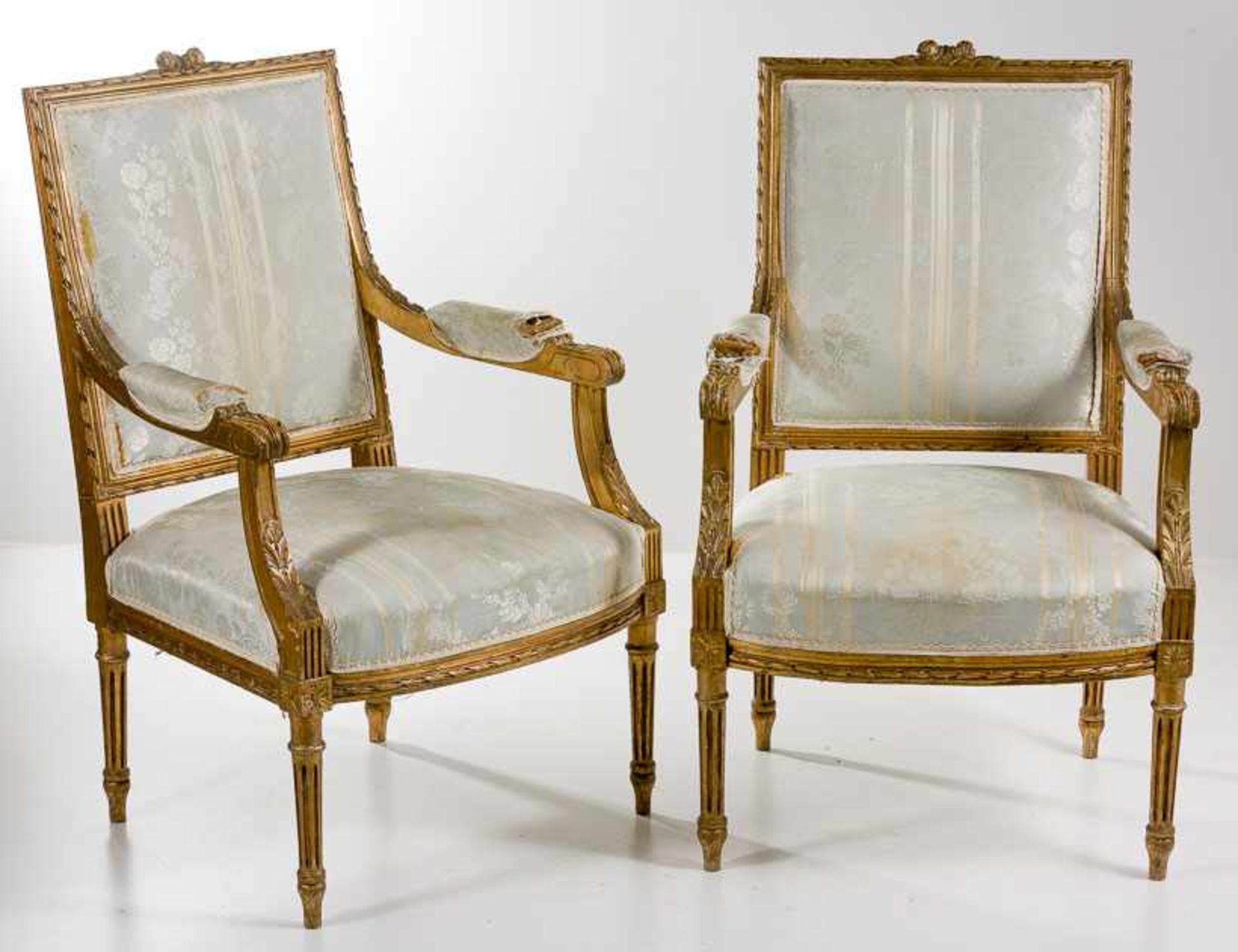 Zwei Armlehnstühle im Louis-XVI-Stil. Holz, vergoldet. Hohe rechteckige Rückenlehne mit