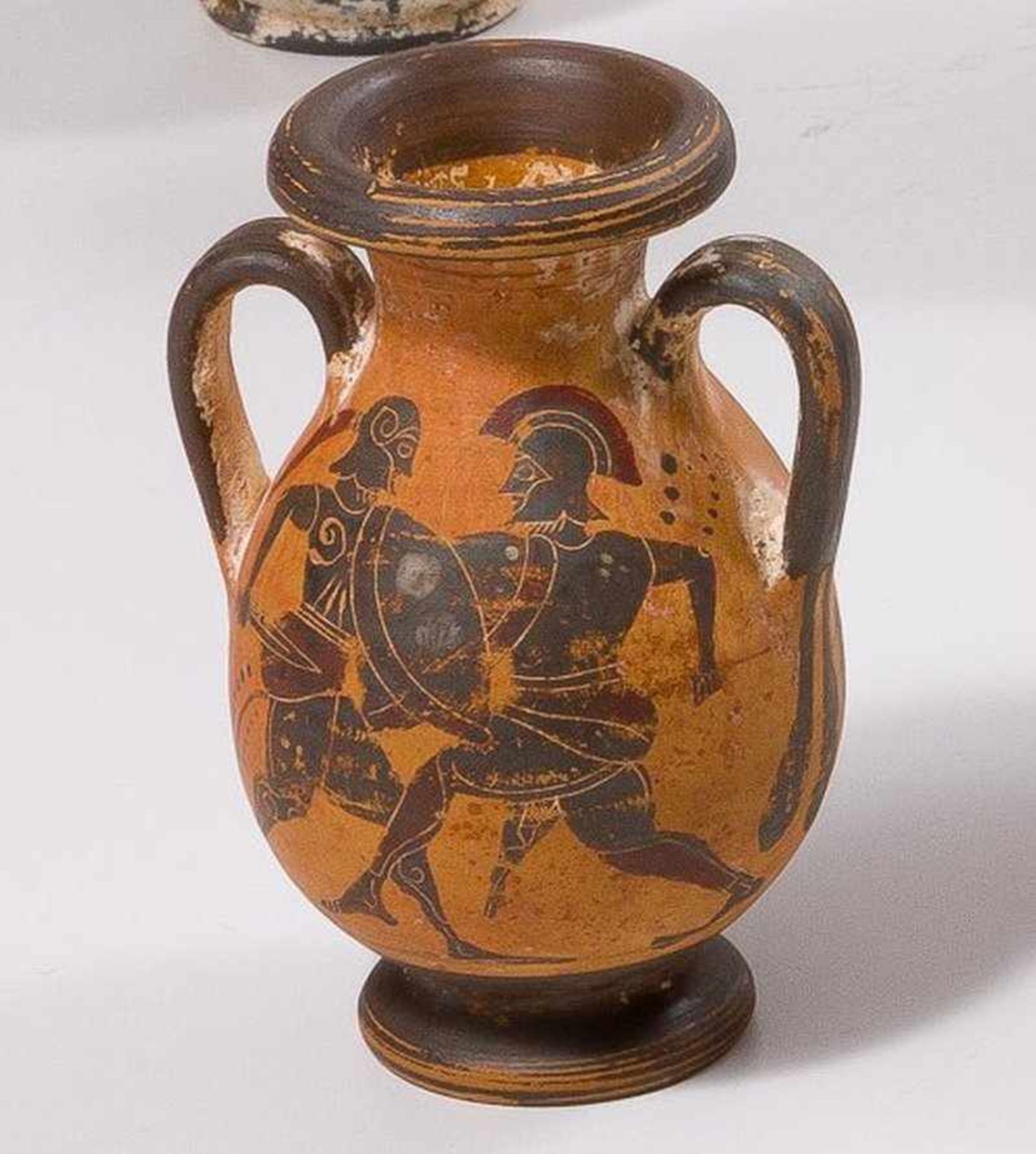 Kleine Henkelamphora mit schwarzfiguriger Malerei. Hellbrauner Ton mit rotbraunem Firnis. Ritzungen.