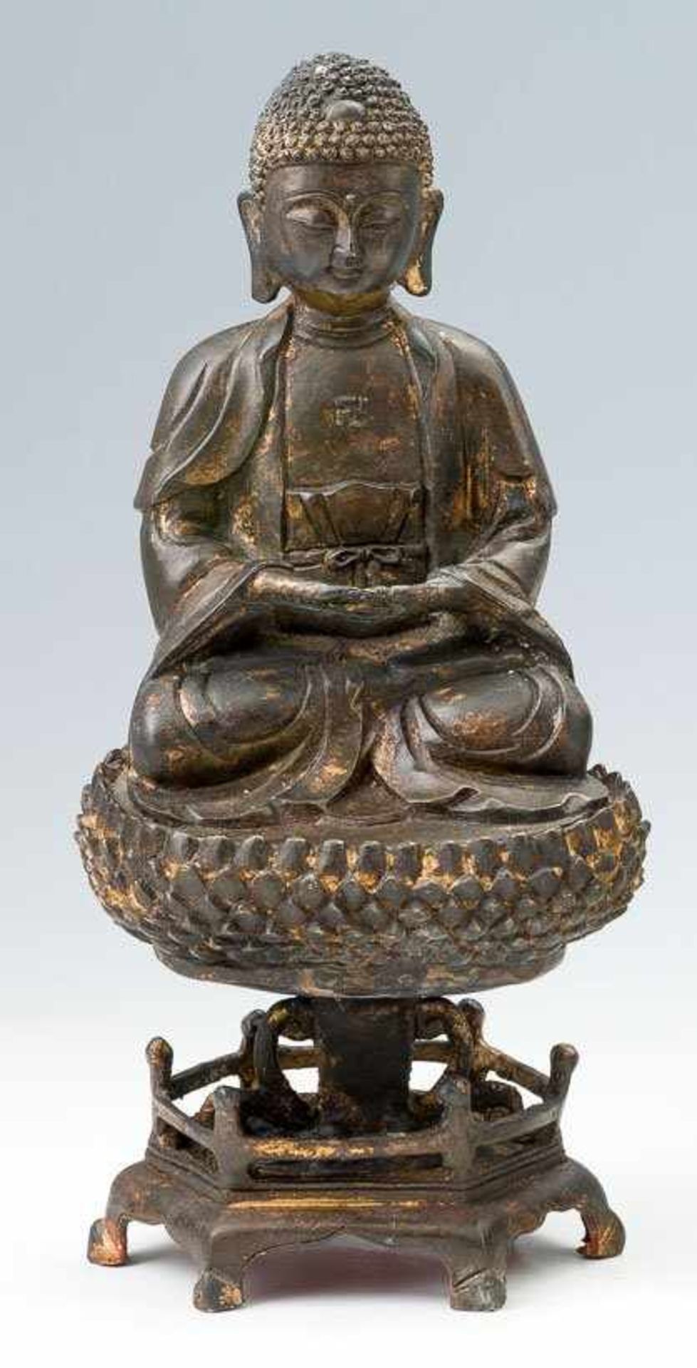 Sitzender Buddha mit zusammengelegten Händen. Bronze, dunkel patiniert u. wenige Reste von