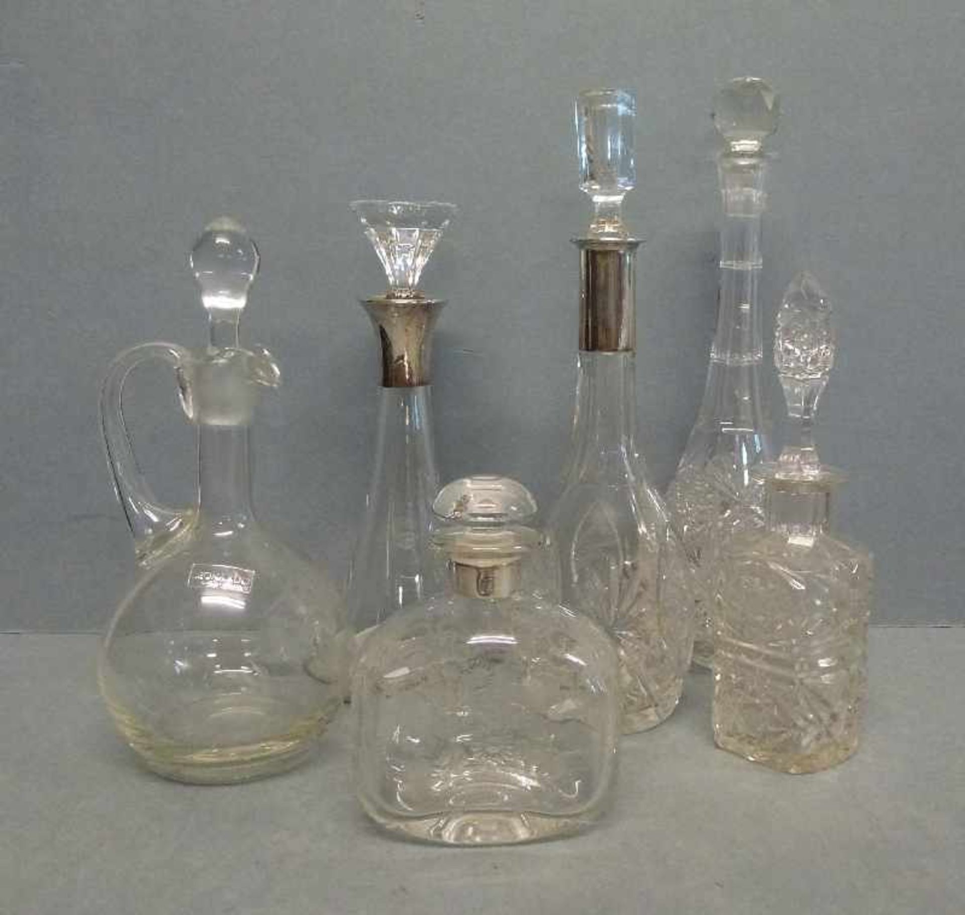 6 Karaffen 3x Silbermanschette, 5x Schliffdekor, eingeschl. Glasstopfen, H 14-30 cm