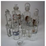 Apothecary. Thirteen clear glass apothecary jars / bottles, mostly with stoppers and labels