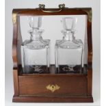 Oak two decanter tantalus with brass mounts & handle, each decanter with frosted floral decoration