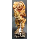 Chinese root carved figure of a sage holding a bat, his left foot raised on his walking stick,