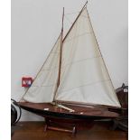 A painted wood yacht model with linen sails upon stand, height overall 42', width 35'