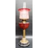 Early 20th Century oil lamp, the etched blush cranberry shade over a cranberry glass reservoir &
