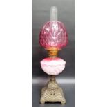 Early 20th Century oil lamp with cranberry dimpled glass ovoid shade over an opaque cranberry