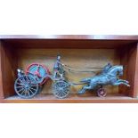 A Victorian style cast iron toy fire cart being pulled by 2 horses & with 2 figures, within later