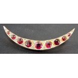 Edwardian rose gold garnet and diamond set crescent brooch, the nine graduated garnets between small