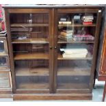Stained pine bookcase with two glazed doors enclosing shelves, height 64.5'.