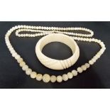 Mother of pearl graduated bead necklace; together with an early 20th Century ivory bangle