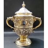 Good Victorian silver gilt lidded twin handled trophy cup, foliate scroll embossed by Goldsmiths &