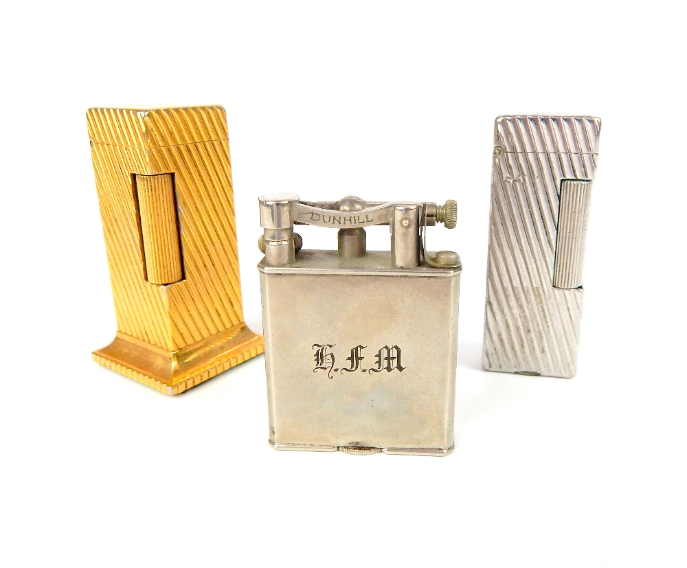 Three Dunhill lighters; gilded tower, 6.6cm, ribbed white metal, & lift arm (3)