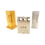 Three Dunhill lighters; gilded tower, 6.6cm, ribbed white metal, & lift arm (3)