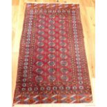 A Bokhara rug with three rows of Turkoman guls on red field within running and frieze borders,