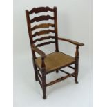 A 19th century oak ladder back open armchair with a rush seat