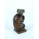 A carved rosewood figurine of a field mouse clutching a nut on a square plinth base, (unclear