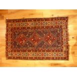 A 19th / early 20th century red ground woollen Shiraz rug, with three central medallions, within a