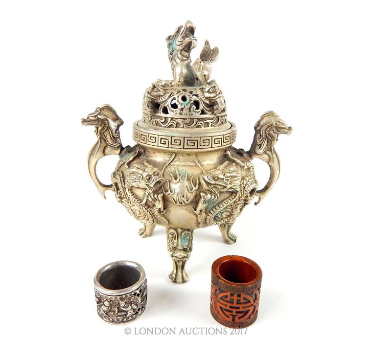 A Chinese white metal twin handled incense burner, the pierced lid cast with a model of a dragon and