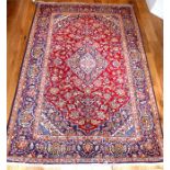 A fine central Persian Kashan rug, with a medallion on a red field decorated with floral designs,