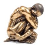 A bronzed resin sculpture of a nude crouching man