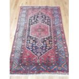 A mid 20th century Persian woollen rug, woven on a red ground with various geometric patterns,