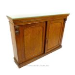A mid Victorian golden oak twin door side cabinet, opening to reveal shelves, with carved moulded