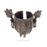 An early 20th century Benin bronze cuff bracelet, cast with three figures, 15cm high, 18cm wide.