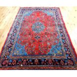 A Large Persian carpet. red ground with central blue medallion and spandrels within multiple