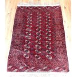 A Persian Bokhara rug, having repeating elephant foot medallions in a red field