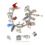 A silver charm bracelet set with many mainly sterling silver charms, with some loose