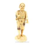 A late 19th / early 20th Japanese ivory Okimono figure of a man holding a hammer in his left hand