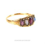 An antique 9 ct yellow gold ring centrally set with graduated opals and garnets, (slender shank),