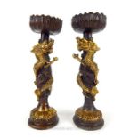 A pair of Chinese bronzed metal candlesticks with a dragon wrapped around each shaft; 23cm high.