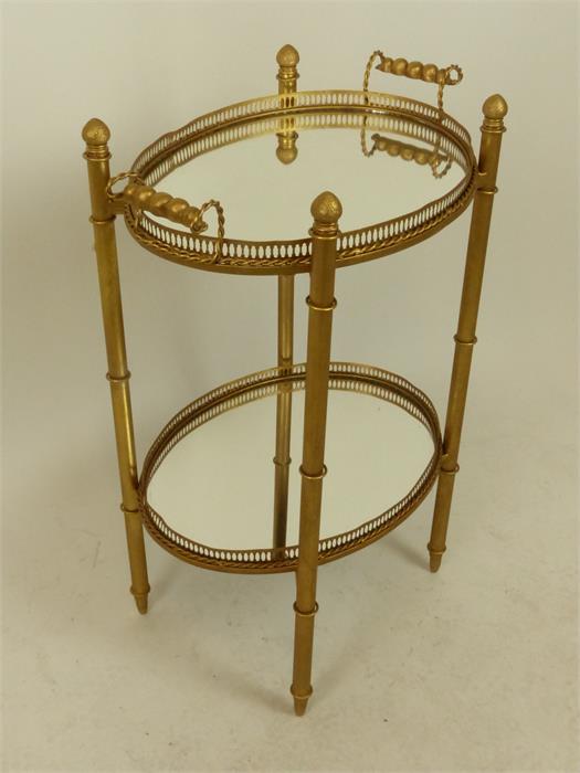 An oval gilt metal galleried mirror drinks tray with carrying handles, on stand with undertier