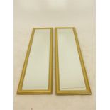 A pair of gilt framed narrow dressing wall mirrors with bevelled plates, 34 x 127 cm