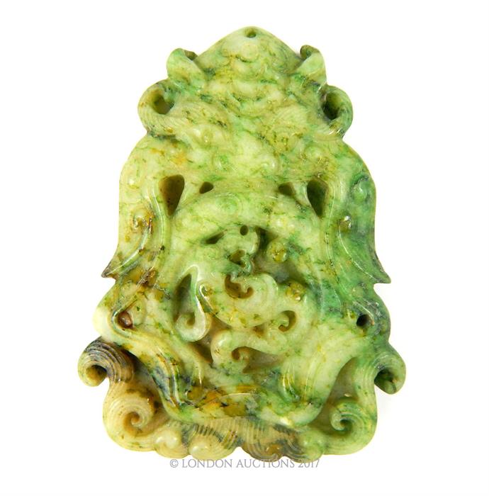 A Chinese carved jade pendant in the form of a mythical creature with a serpent between its jaws