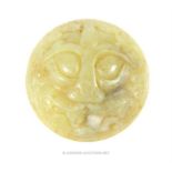A Chinese carved jade disc form brooch decorated with a grotesque mask