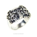 A gentleman's silver ring inset with skulls; stamped "935".