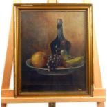 An Edwardian oil on canvas still life study of a bowl of fruit and a bottle