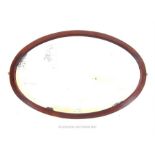 A late Victorian oval mahogany wall mirror, having original bevelled plate